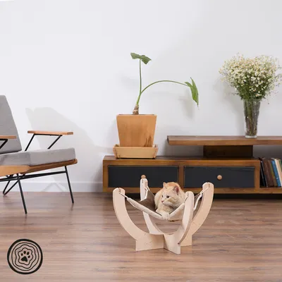 Mobile sospeso in legno per pet con tessuto beige, gatto sdraiato all'interno. Soggiorno moderno con mobili in legno e piante sullo sfondo.