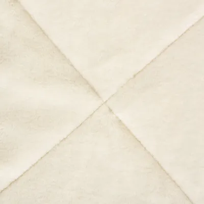 Close-up of a cream-coloured, soft fabric with diagonal seams. Material texture visible.