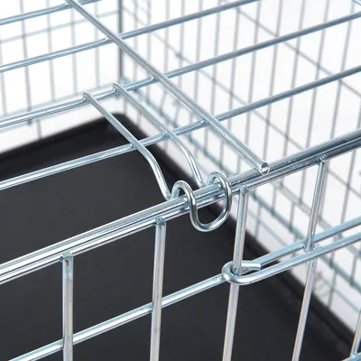 Yksityiskohtainen näkymä metallihäkistä, jossa on tukevat kalterit ja turvallinen lukitusmekanismi. Musta pohjalevy näkyvissä.