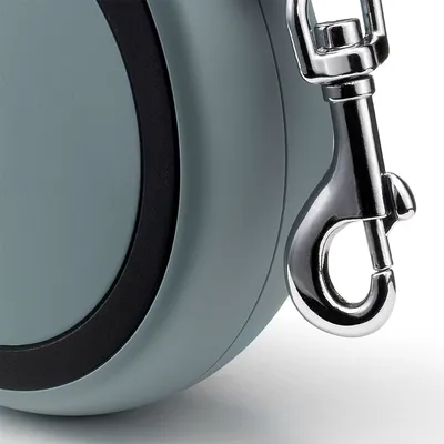 Primo piano di moschettone in metallo e parte del corpo in plastica di un guinzaglio avvolgibile per pet, senza marchi visibili.