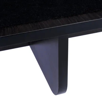 Primo piano di una gamba in legno nera e di un piano del tavolo scuro con superficie in feltro.