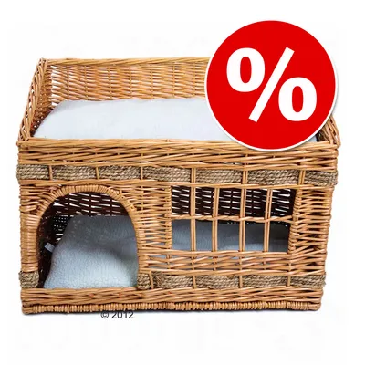 Cesta de mimbre para mascotas con dos niveles y cojines blancos, símbolo de porcentaje en círculo rojo indicando oferta o descuento visible en la esquina superior derecha.