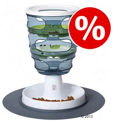 Comedero interactivo Catit Senses de plástico con croquetas en el interior y símbolo de porcentaje rojo indicando oferta o descuento visible.