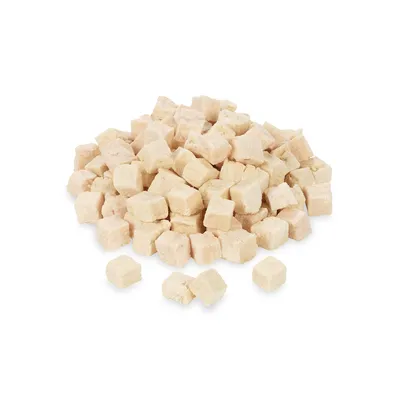 Montón de dados pequeños de alimento deshidratado para mascotas, color beige claro, sin marca ni texto visible.