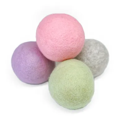 Quatre balles en feutre aux couleurs pastel : rose, violet, vert et gris.