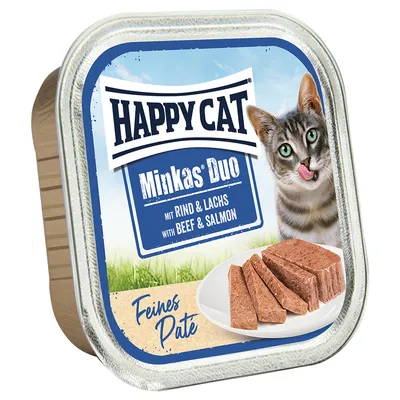 Happy Cat Minkas Duo z wołowiną i łososiem, delikatny pasztet. Na zdjęciu: karma dla kotów w formie pasztetu na białym talerzu i kot w tle.