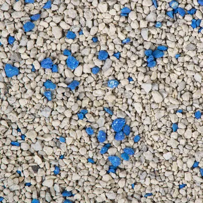 Vista cercana de arena para gatos compuesta por gránulos beige y fragmentos azules. No se muestra marca ni envase.