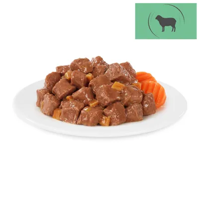 Close-up of meat pieces in sauce with carrot slices on a white plate. Green symbol with silhouette of a sheep at the top right.