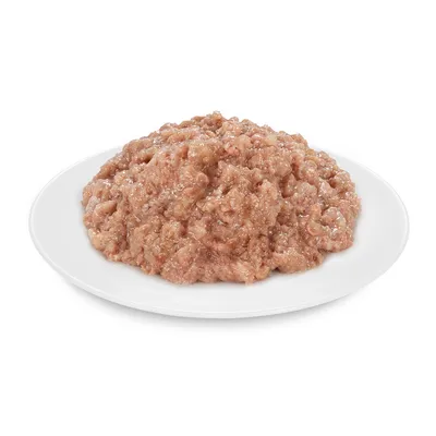 Apróra vágott, nedves állateledel fehér tányéron, mártásban. Márka és terméknév nem látható.