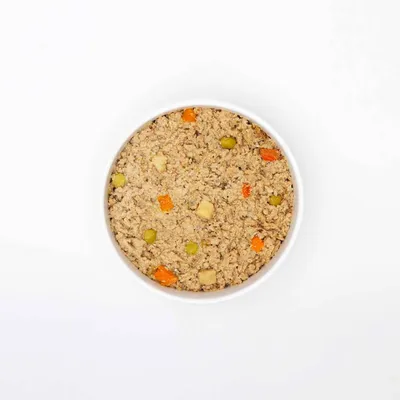 Bowl containing moist pet food with visible chunks of vegetables such as carrots and peas, showing texture and ingredients for product identification.
