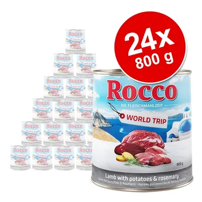 Pack de 24 latas de 800 g Rocco World Trip, cordero con patatas y romero. Texto visible en inglés: Lamb with potatoes & rosemary. Imagen de carne y paisaje mediterráneo en la etiqueta.