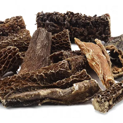 Mix di snack per cani composti da pezzi di trippa essiccata e altri masticativi naturali, senza confezione visibile.