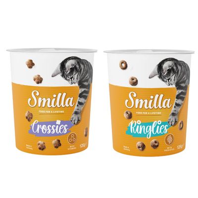 Due confezioni di snack per gatti Smilla, varianti Ringlies e Crossies da 125 g, con scritte 'with prebiotics' e 'with vitamins'. Bollino arancione con testo: Provami!