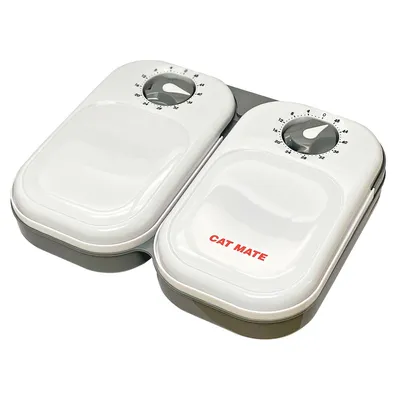 Automatisk foderskål med to hvide låg, drejeknapper med tidsindstilling og rød tekst: CAT MATE. Skålen er lavet af plastik. Automatisk foderskål med to hvide låg, drejeknapper med tidsindstilling og rød tekst: CAT MATE. Skålen er lavet af plastik.