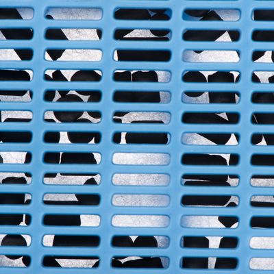 Närbild av ett blått plastgaller med svarta föremål bakom, troligen en del av ett filter eller en behållare.
