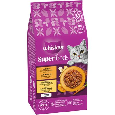 Katten äter ur en matskål som hålls av en person. Whiskas-logotypen syns nere till höger.