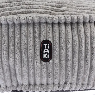 Logo Tiaki na šedé, žebrované tkanině. Detailní pohled na produkt.