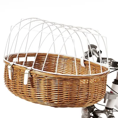 Panier en osier fixé à un vélo, muni d’une grille métallique blanche et de deux sangles blanches visibles sur le côté. Guidon de vélo partiellement visible.