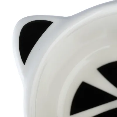 Close-up of a white ceramic bowl with black geometric patterns and cat ear-shaped design.