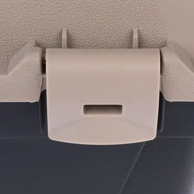 Nærbillede af en beige-grå lukkemekanisme i plast, der forbinder to dele af en transportkasse.