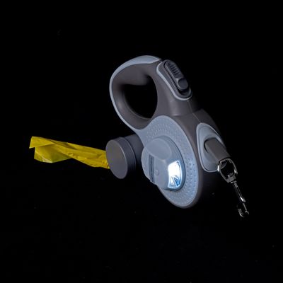 Correa gris para perros con luz LED integrada, mecanismo retráctil y dispensador de bolsas amarillo.