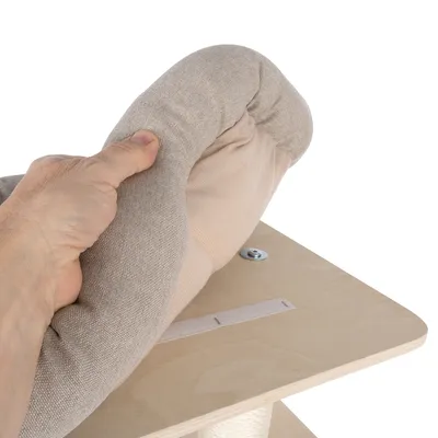 Main tenant un coussin en tissu beige sur une plateforme en bois fixée par une vis, montrant l’installation ou le retrait du coussin.