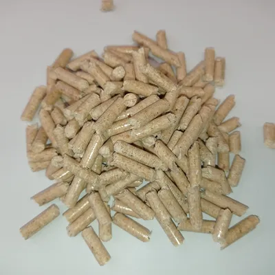 Lähikuva ruskeista, sylinterinmuotoisista pelleteistä valkoisella taustalla. Tuotetiedot eivät näkyvissä.