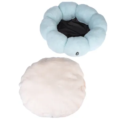 Round, light blue pet bed with padded edge and black interior. Beige, round cushion placed separately next to it.
