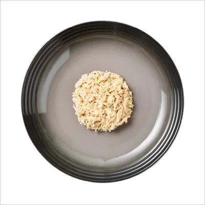 Primo piano di carne di pollo tritata su un piatto grigio, presentata come esempio della consistenza e dell’aspetto del prodotto.