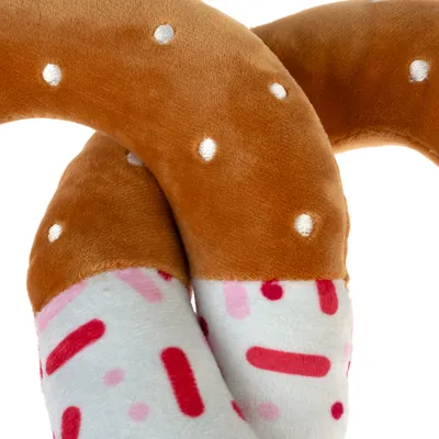 Jouet pour animal en peluche, forme torsadée, partie marron à pois blancs et partie blanche avec motifs rouges et roses. Matière textile douce visible.