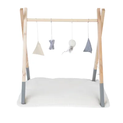 Träställning med hängande leksaker: tygtriangel, randigt tygkors, boll med fjäder och tygtriangel. Underlag av vit plysch.