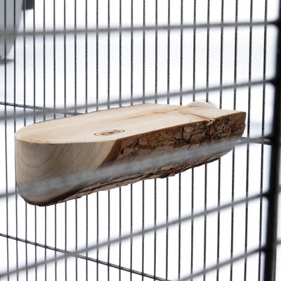 Holzplattform mit Rinde, befestigt an den Gitterstäben eines Käfigs.