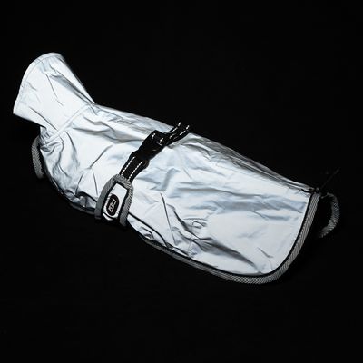 Zilverkleurige hondenjas met reflecterend materiaal, verstelbare riemen en zwarte sluiting. Geschikt voor koude of donkere omgevingen.