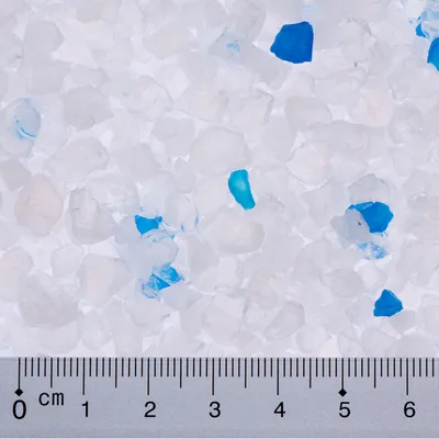 Close-up of white and blue silica litter crystals with a centimetre scale for size determination.