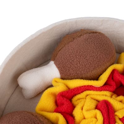 Speelgoed van stof in de vorm van een bruine kippenpoot met wit bot, omgeven door rode en gele stoffen stroken.