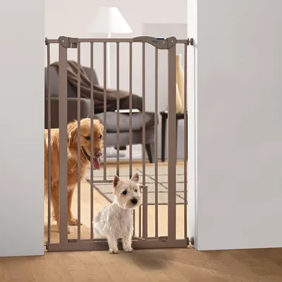 Türschutzgitter aus Metall mit kleiner Durchgangstür, geeignet für Haustiere. Zwei Hunde hinter dem Gitter in einem Wohnzimmer sichtbar.