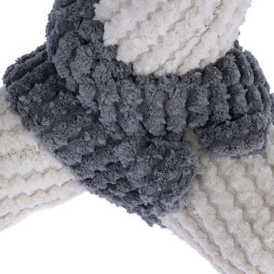 Prim-plan al unei jucării din material textil moale, texturat, în gri și alb. Material cu model ondulat și suprafață pufoasă.