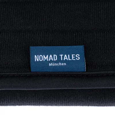 Nomad Tales München. Merkkietiketti mustalla kankaalla.