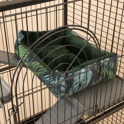 Grön, vadderad kudde med tropiskt bladmotiv i en metallbur. Lämplig för användning i djurburar.