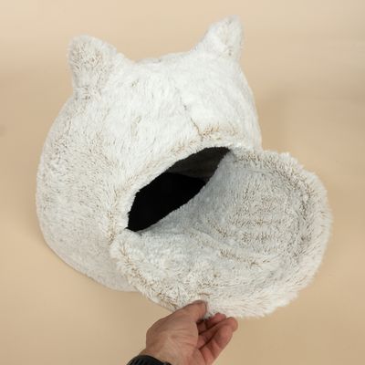 Biele, nadýchané pelech pre domáce zvieratá s dizajnom uší a snímateľným poťahom. Ruka ukazuje otvor pelechu.