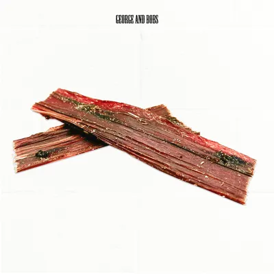 George and Bobs. Två remsor torkat kött med kryddor, rödbrun färg. George and Bobs. Två remsor torkat kött med kryddor, rödbrun färg.