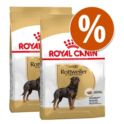 2 sacos de pienso Royal Canin Adult Rottweiler, imagen del perro en el envase y símbolo de porcentaje en círculo naranja indicando oferta o descuento visible.