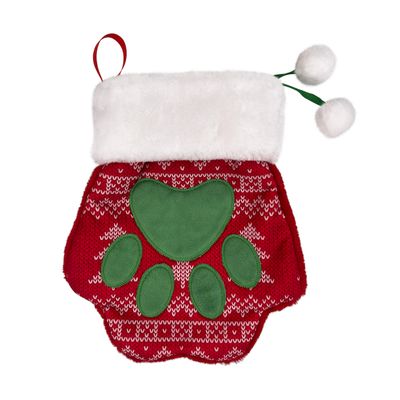 Chaussette de Noël en forme de patte, tricot rouge à motifs blancs, grande empreinte verte, bordure blanche en tissu peluche et deux pompons blancs attachés par des rubans verts.