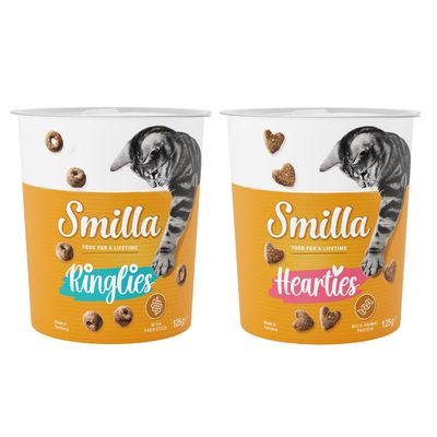 Due confezioni di snack per gatti Smilla, varianti Ringlies e Crossies da 125 g, con scritte 'with prebiotics' e 'with vitamins'. Bollino arancione con testo: Provami!