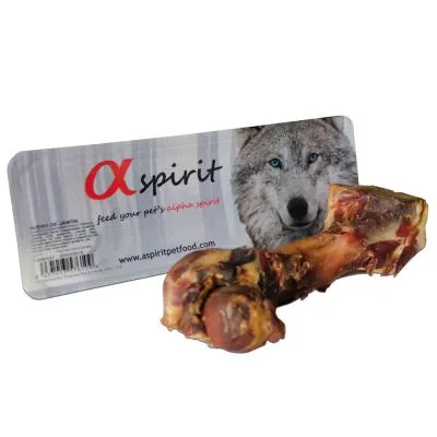 Kość dla psa przed opakowaniem z widocznym napisem: alpha spirit, www.aspiritpetfood.com oraz zdjęciem wilka. Widoczny fragment tekstu po angielsku.