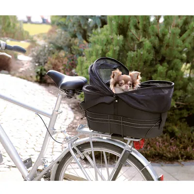 Cestino nero per animali montato sul portapacchi di una bicicletta, con un piccolo cane all'interno. Il cestino ha copertura in rete visibile.