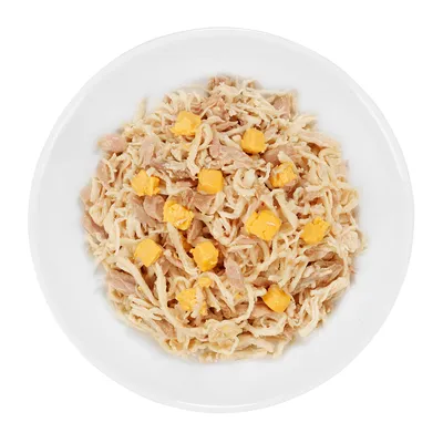 Detailný záber na biely tanier s nasekaným kuracím mäsom a žltými kockami syra, viditeľné ako ingrediencie produktu.