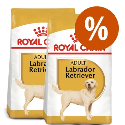 Due sacchi di crocchette Royal Canin Adult Labrador Retriever con simbolo percentuale bianco su sfondo arancione, indicante offerta o sconto.