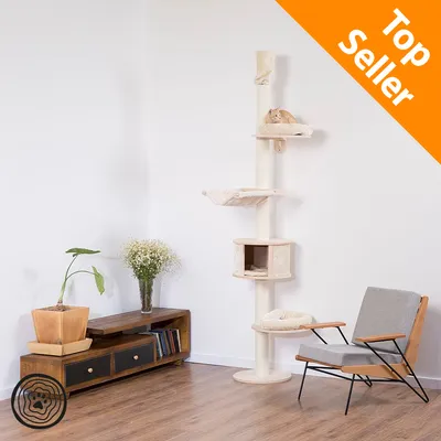 Tiragraffi a colonna con più ripiani e cuccia, gatto visibile su uno dei piani. Angolo della stanza con mobile basso, pianta, fiori e poltrona. Testo in alto: Top Seller.