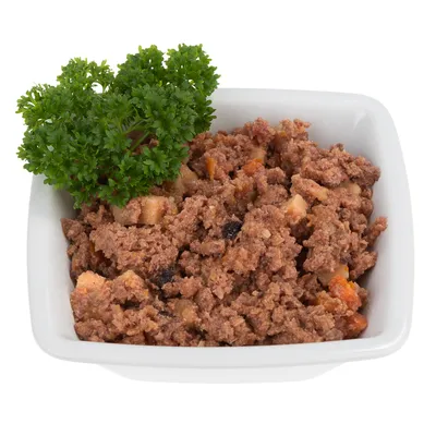 Pâtée en morceaux dans une coupelle blanche, garnie de persil frais. Mélange visible de viande hachée et petits morceaux de légumes.